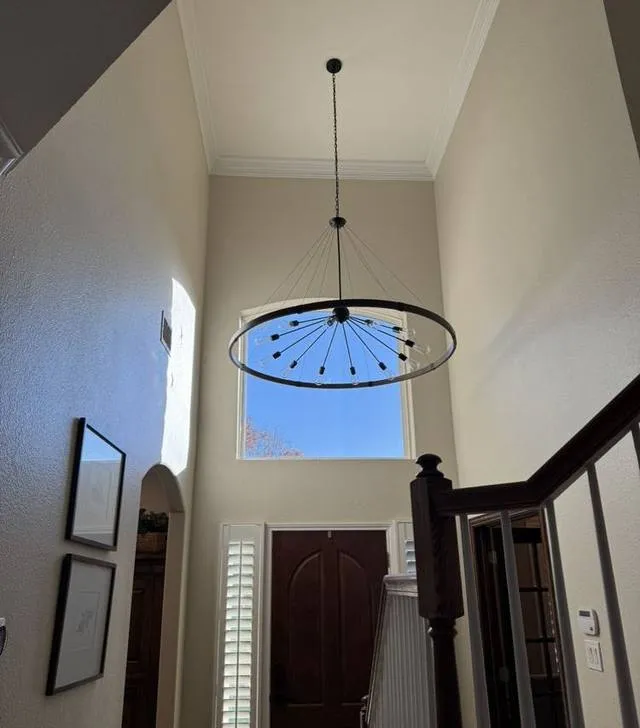 Stairwell light fixture installed from a ladder on a two-story landing